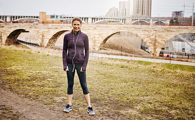 Buy stock photo Full length portrait of an attractive young woman listening to music while running alongside the city