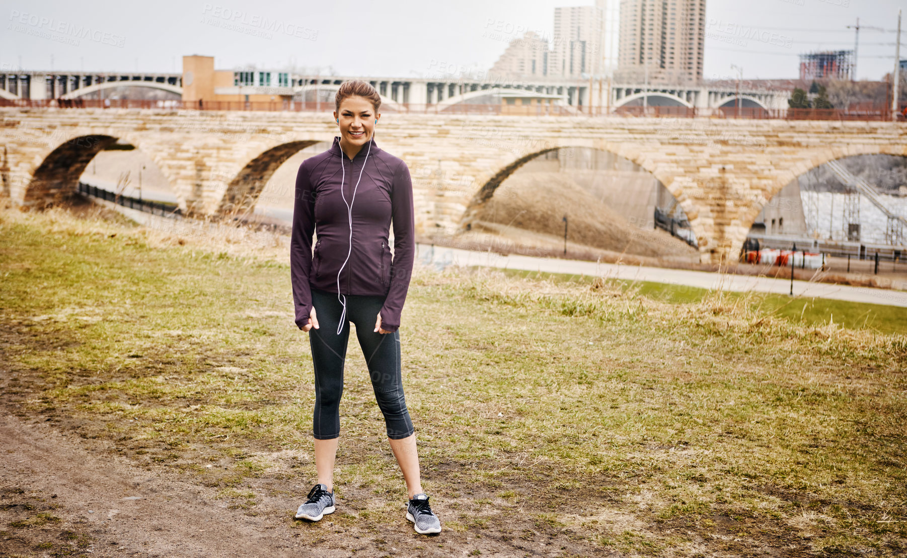 Buy stock photo Full length portrait of an attractive young woman listening to music while running alongside the city