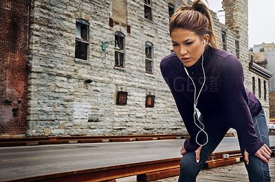 Buy stock photo Cropped shot of an attractive young woman listening to music while running through the city