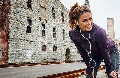 Buy stock photo Cropped shot of an attractive young woman listening to music while running through the city