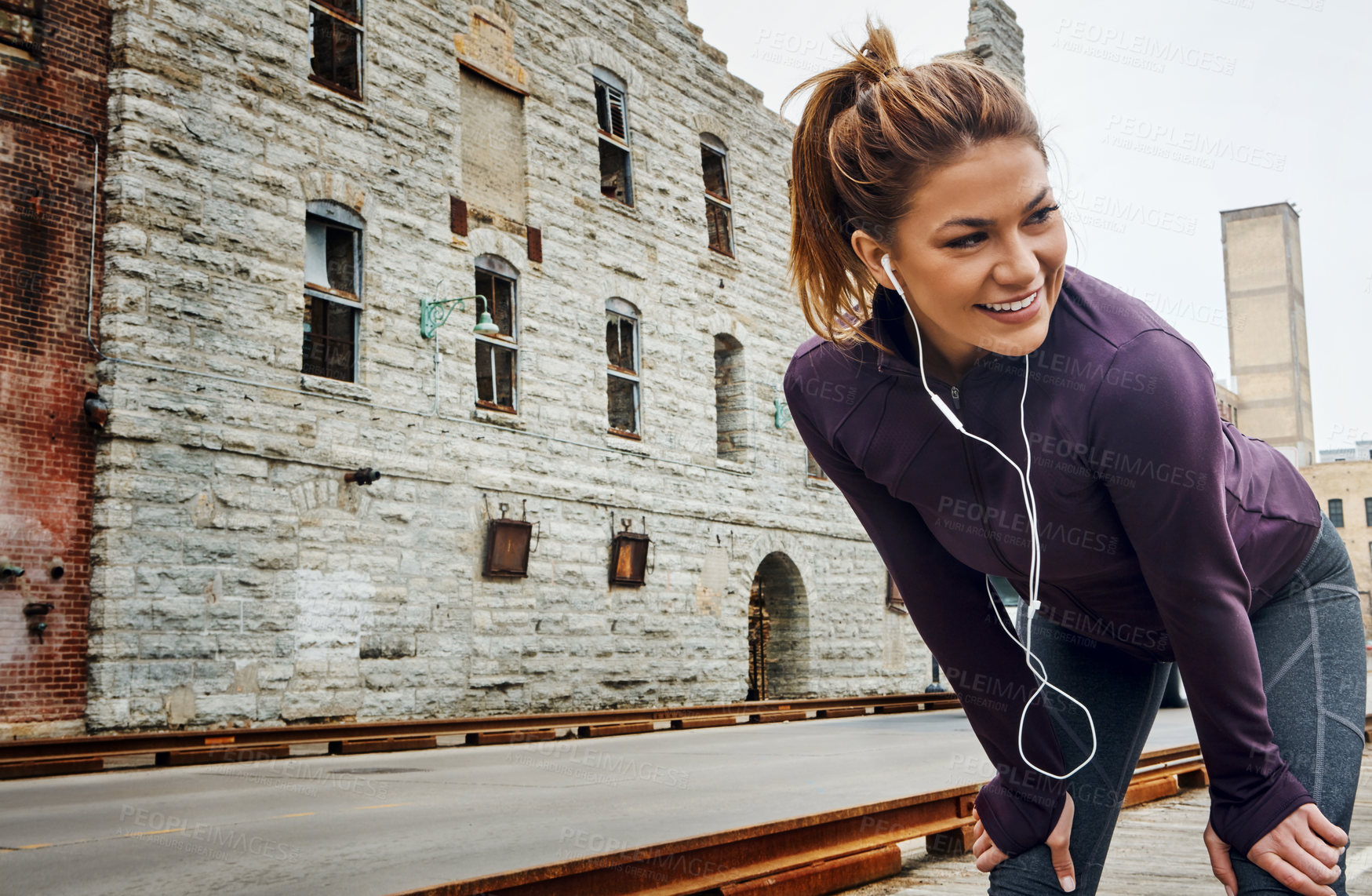 Buy stock photo Cropped shot of an attractive young woman listening to music while running through the city