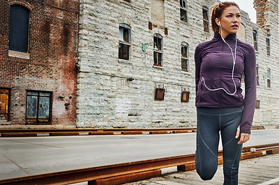 Buy stock photo Cropped shot of an attractive young woman listening to music while running through the city