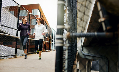 Buy stock photo Full length shot of two attractive young women running through the city