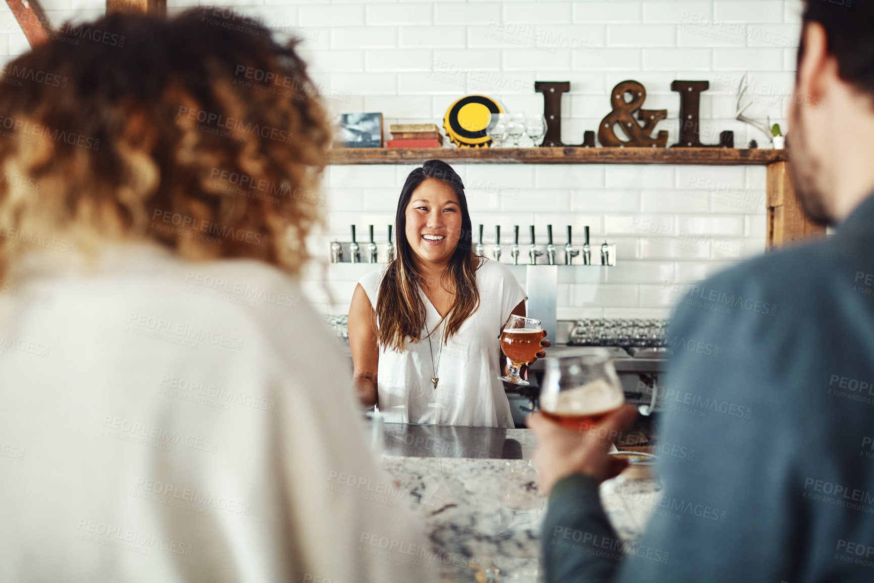 Buy stock photo Shot of a young woman serving drinks in a bar 