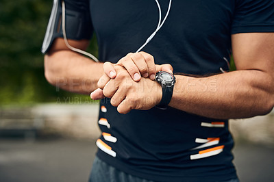 Buy stock photo Closeup shot of a sporty young man checking his wristwatch while exercising outdoors