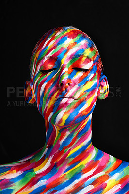 Buy stock photo Studio shot of a young woman posing with brightly colored paint on her face against a black background