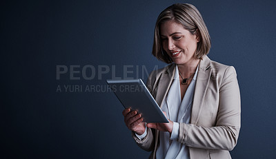 Buy stock photo Studio shot of an attractive young corporate businesswoman using a tablet against a dark background