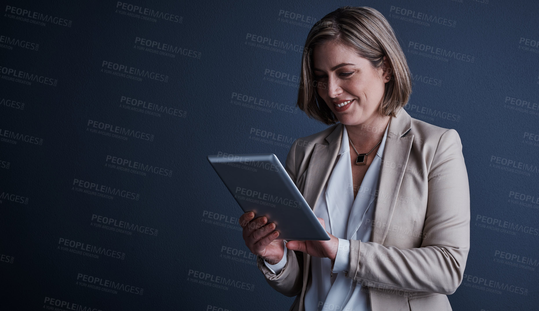 Buy stock photo Studio shot of an attractive young corporate businesswoman using a tablet against a dark background