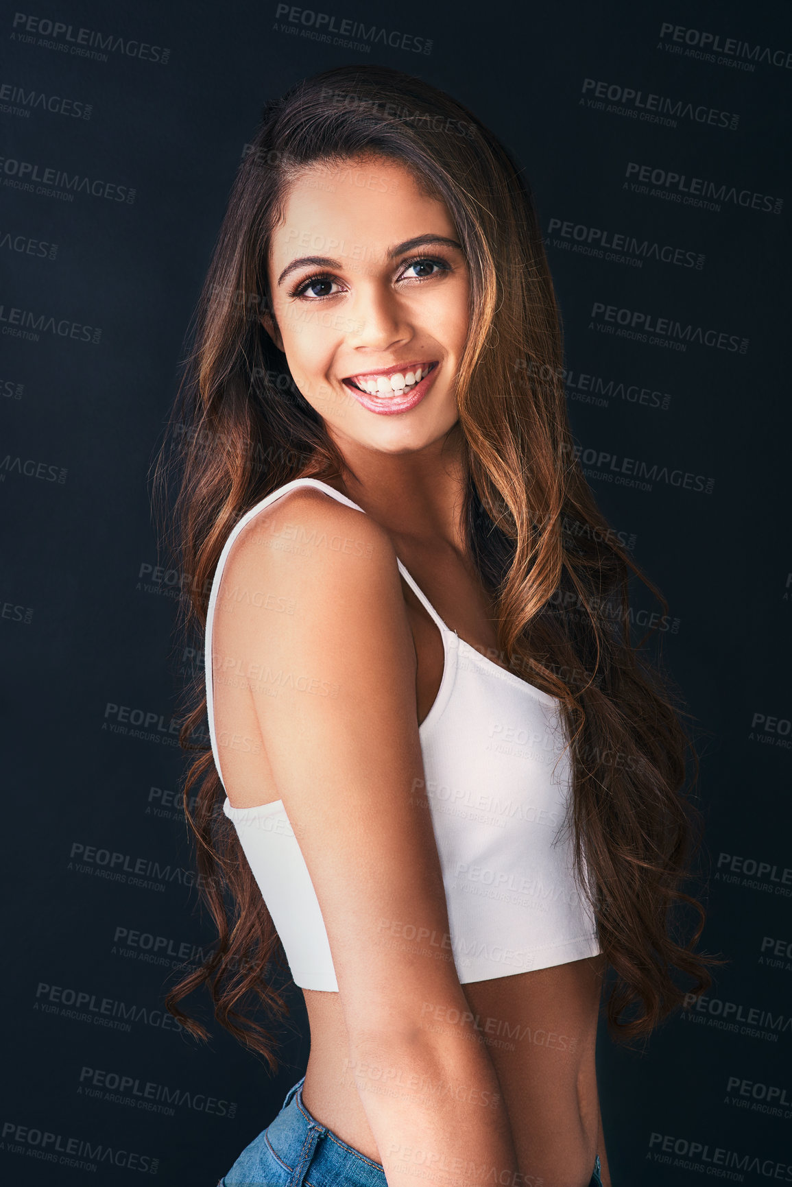 Buy stock photo Studio portrait of an attractive young woman posing against a dark background