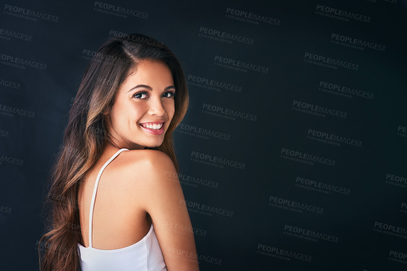 Buy stock photo Studio portrait of an attractive young woman posing against a dark background