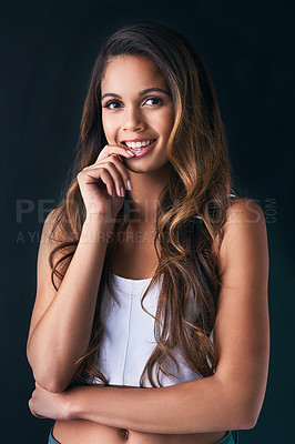Buy stock photo Studio portrait of an attractive young woman posing against a dark background