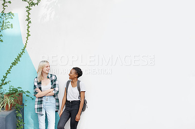Buy stock photo Shot of two young and cheerful students having a conversation outside before class