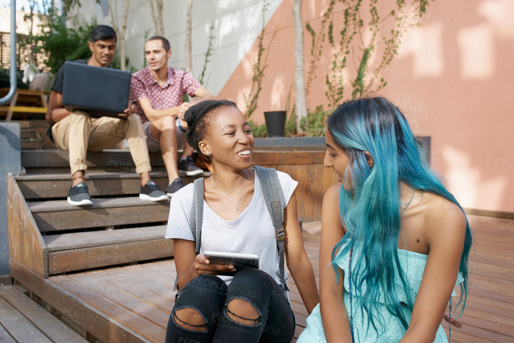 Buy stock photo Students, laptop and tablet for college break with conversation, talking and chatting with smile. Friends, boys and girls on wooden stairs for sitting, relaxing and laughing with electronics or tech