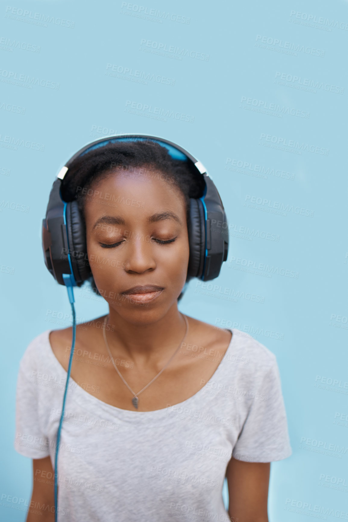 Buy stock photo Black woman, headphones and listening to music for peace, wireless technology and eyes closed on blue background. Calm, zen and meditation with radio playlist, podcast or wellness audio in studio