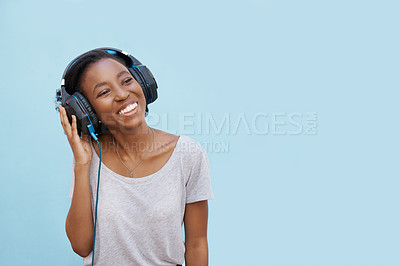 Buy stock photo Happy, music and black woman with earphones in studio for streaming, sound or podcast on blue background. Remember, smile and gen z student with earphones, reflection or idea, hearing or radio news