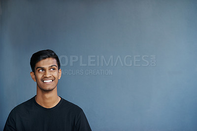 Buy stock photo Studio shot of a cheerful young man smiling while being in deep thought
