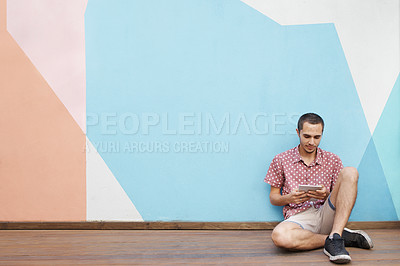 Buy stock photo Male student, sitting on floor and tablet for video streaming, mobile learning or virtual entertainment indoor. Young man, relax and tech for online internet and social media on break with mockup 