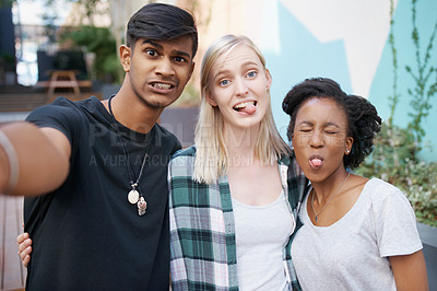 Buy stock photo Shot of a group of happy young friends taking selfies together outside