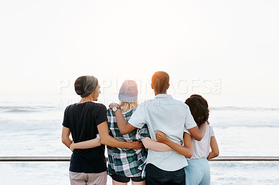 Buy stock photo Sunshine, hug and back of friends by ocean for holiday, summer vacation and relax outdoors. Diversity, promenade and men and women embrace by seaside for travel, weekend and fun together for bonding