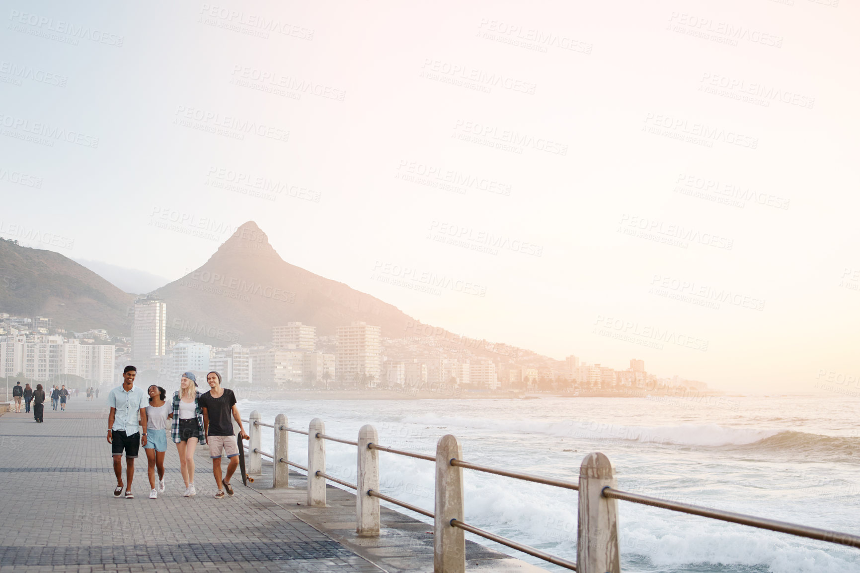 Buy stock photo Full length shot of a group of young friends walking on the promenade