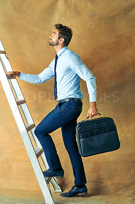 Buy stock photo Studio shot of a young handsome businessman posing against a brown background 