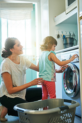 Buy stock photo Help, home and mother with kid at washing machine for chores, teaching and learning housekeeping routine. Laundry, mom and daughter cleaning clothes together with support, care and child development.