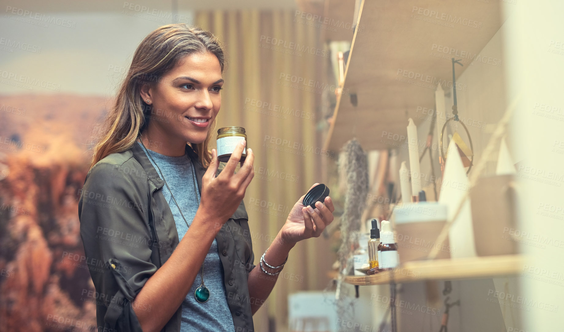 Buy stock photo Woman, customer and smile with oil jar at shop for shopping, skincare and wellness. Female person, consumer and happy or satisfied at shelf for cream, organic product and cosmetics for self care