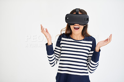 Buy stock photo Studio shot of a young woman looking amazed while wearing a VR headset against a white background