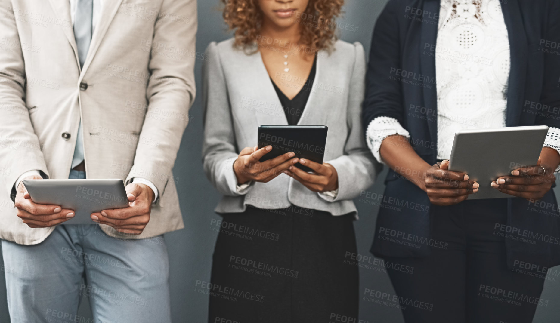 Buy stock photo Shot of a group of unrecognisable businesspeople using their digital tablets while waiting for a job interview