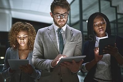 Buy stock photo Shot of a group of businesspeople working late on digital tablets in an office