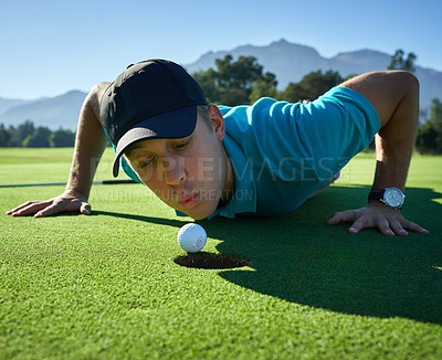 Buy stock photo Low angle shot of a carefree young man blowing a golf ball into a hole on a golf course