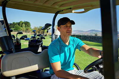 Buy stock photo Shot of a cheerful young man driving in a golf cart to the next hole on a golf course