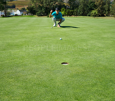 Buy stock photo Shot of a focused young man waiting for the golfball he just hit to go into a hole outside on a golf course