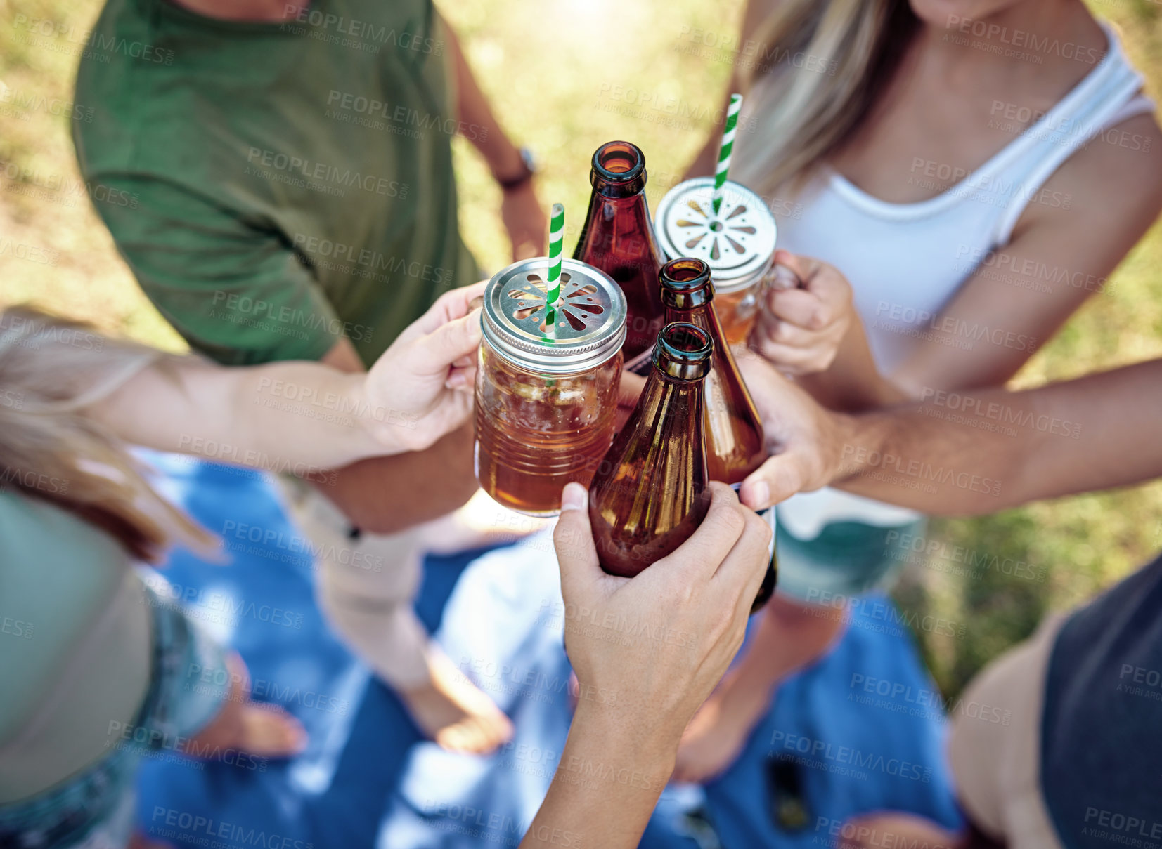 Buy stock photo High angle shot of a young group of friends toasting while enjoying a few drinks outside in the summer sun