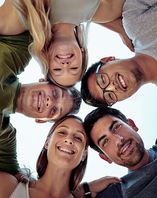 Buy stock photo Low angle portrait of a young group of friends standing outside in a huddle