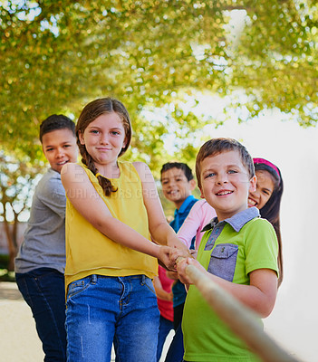 Buy stock photo Shot of a diverse group of children playing tug of war outside