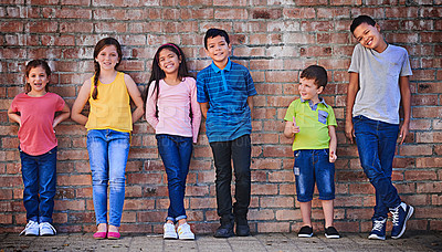 Buy stock photo Shot of a diverse group of children standing against a wall outside