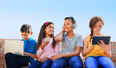 Buy stock photo Shot of a diverse group of children having fun with technology outside