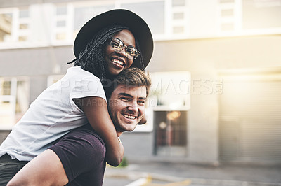 Buy stock photo Young playful interracial couple playing, bonding and hugging while standing in the city together on weekend. Happy husband giving wife a piggyback ride, enjoying a day in the urban town or traveling