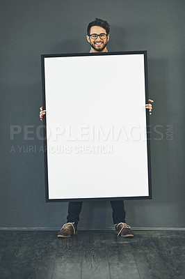 Buy stock photo Man standing with a blank sign or portrait frame, showing copy space for advertising or marketing with dark background. Happy, smiling and intelligent guy holding big white poster or page copyspace 