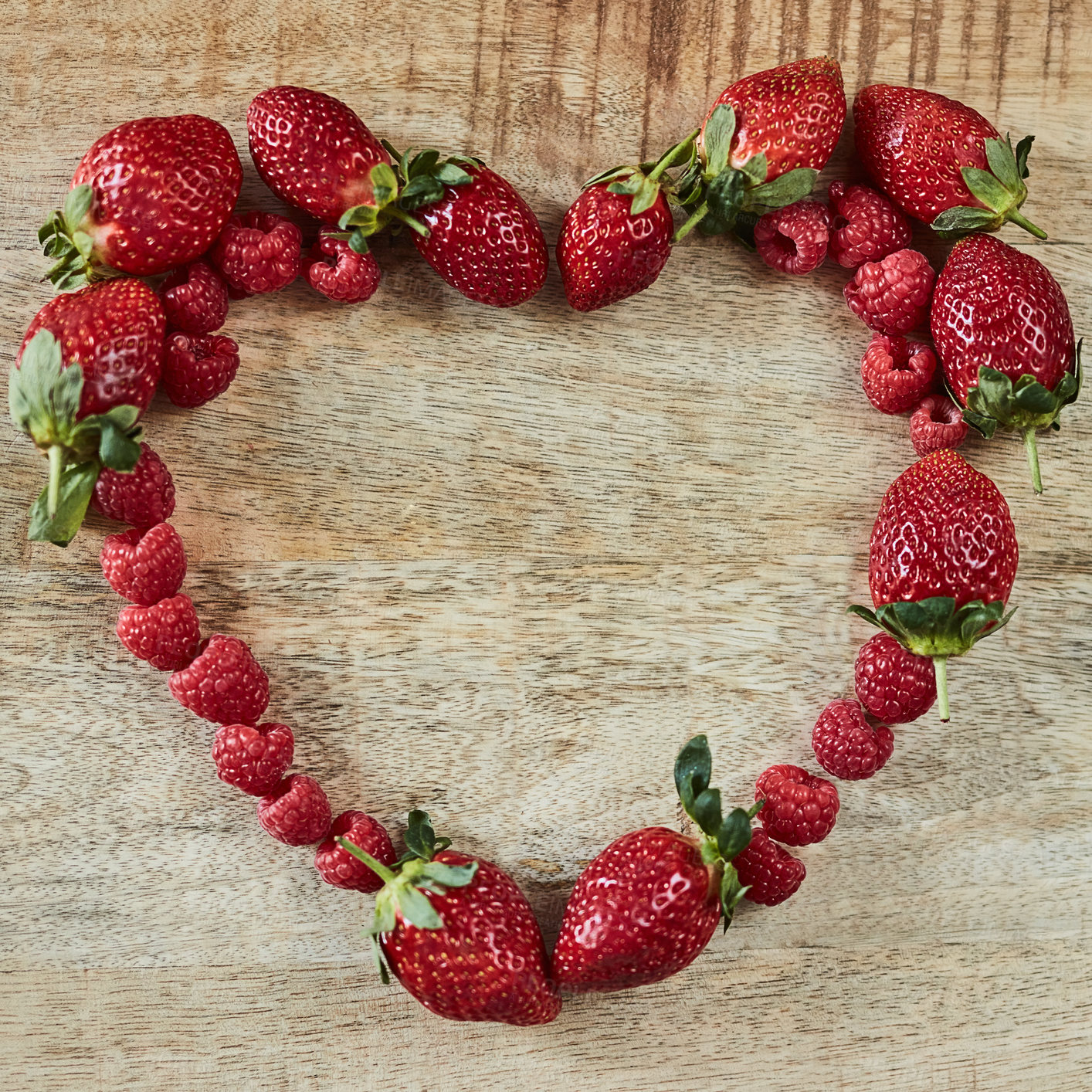 Buy stock photo Shot of strawberries forming a heart shape on a wooden table