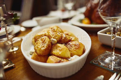 Buy stock photo Closeup shot of a bowl of roast potatoes on a dining table