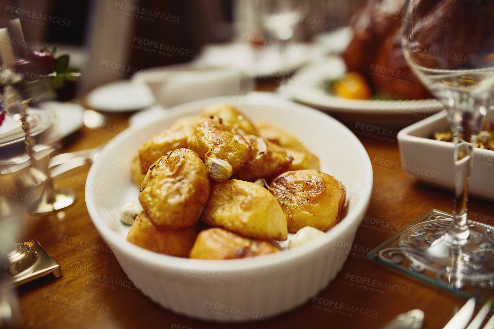 Buy stock photo Closeup shot of a bowl of roast potatoes on a dining table