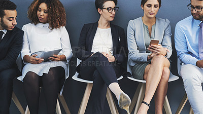 Buy stock photo Business people waiting in line and sharing information with technology. Professionals sitting in a row for an interview against a grey background. A digital marketing team collaborate and network 