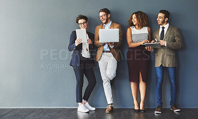 Buy stock photo Studio shot of a group of businesspeople using wireless technology together while standing in line against a gray background