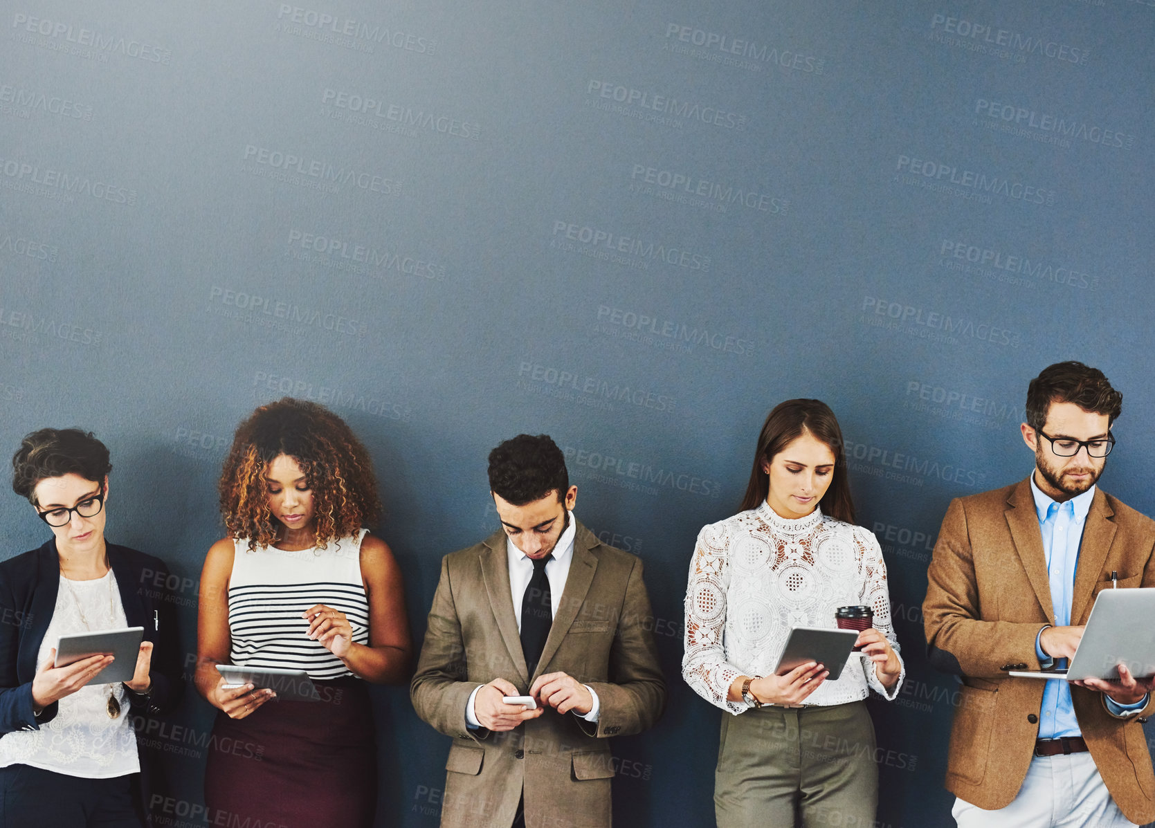 Buy stock photo Studio shot of a group of businesspeople using wireless technology while waiting in line against a gray background