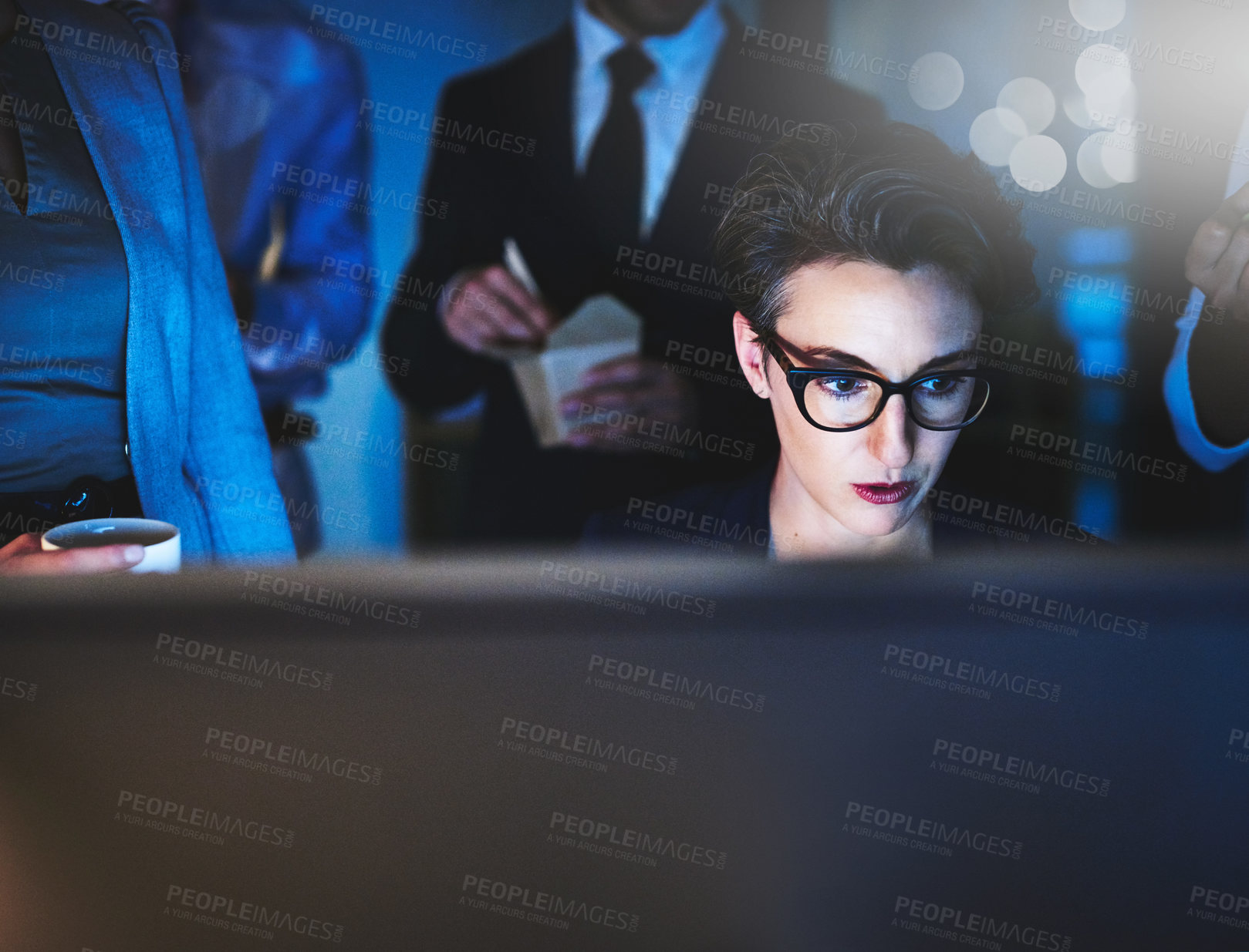 Buy stock photo Cropped shot of a young woman working late with colleagues standing in the background