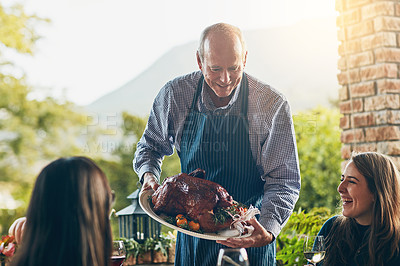 Buy stock photo Shot of a man bringing a freshly cooked turkey to the dining table