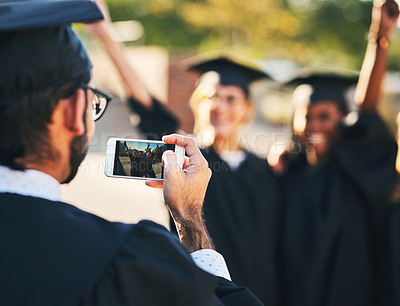 Buy stock photo Shot of a group of students taking pictures with a mobile phone on graduation day