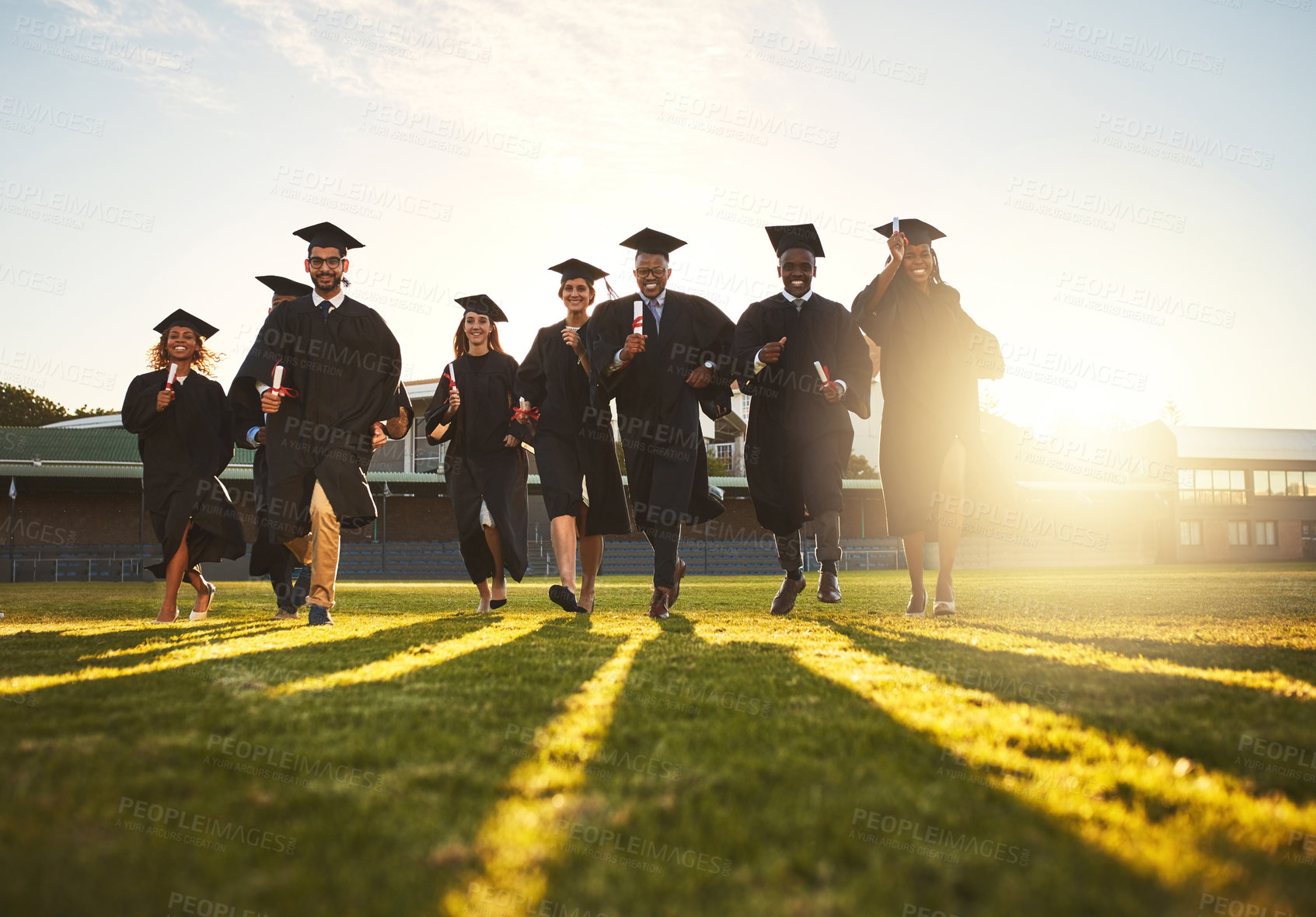 Buy stock photo Graduation, group running and campus lawn with college success, student celebration and diploma event at university. Friends, outdoor and academy achievement with ceremony, people and happy of future